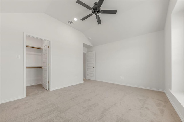 unfurnished bedroom with light carpet, ceiling fan, a spacious closet, a closet, and lofted ceiling