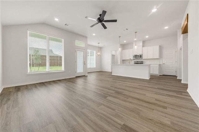 unfurnished living room featuring wood-type flooring, ceiling fan with notable chandelier, lofted ceiling, and sink