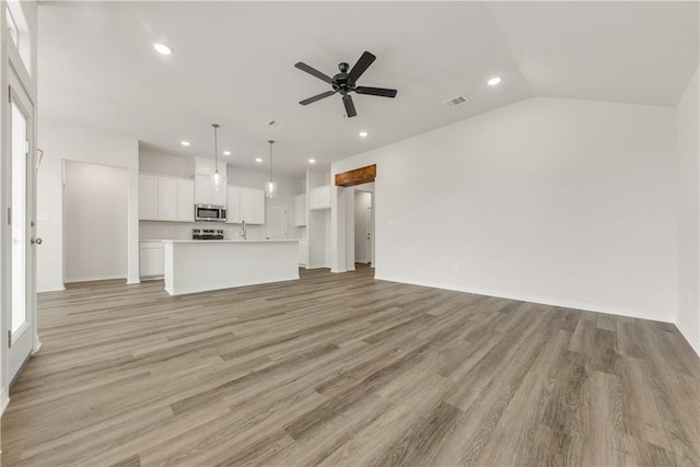 unfurnished living room with ceiling fan, vaulted ceiling, and light hardwood / wood-style flooring