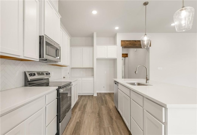 kitchen with pendant lighting, sink, light hardwood / wood-style flooring, appliances with stainless steel finishes, and white cabinetry