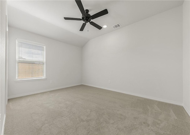 spare room featuring light carpet, ceiling fan, and vaulted ceiling