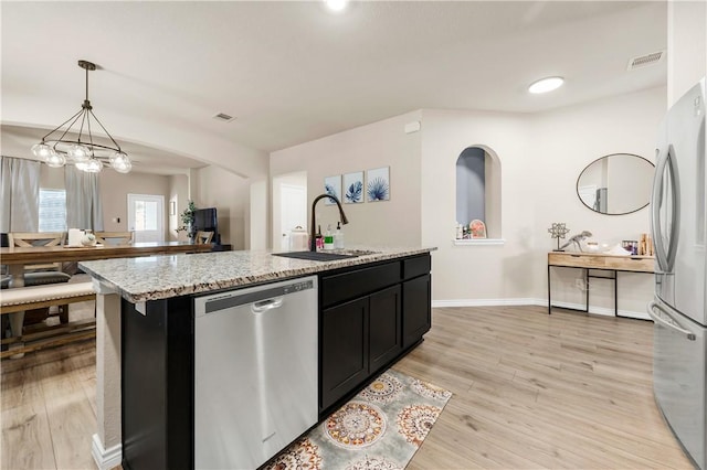 kitchen featuring sink, an island with sink, stainless steel appliances, and light hardwood / wood-style floors