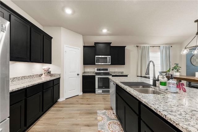 kitchen featuring pendant lighting, sink, light wood-type flooring, light stone counters, and stainless steel appliances