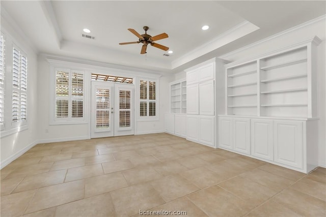 unfurnished room featuring built in shelves, ceiling fan, french doors, a tray ceiling, and ornamental molding