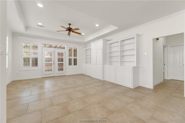 tiled empty room with built in features, a raised ceiling, ceiling fan, and crown molding