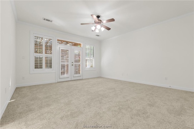 empty room featuring a wealth of natural light, crown molding, ceiling fan, and light carpet