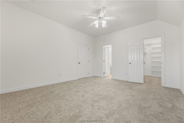 unfurnished bedroom featuring a spacious closet, ceiling fan, light carpet, and lofted ceiling