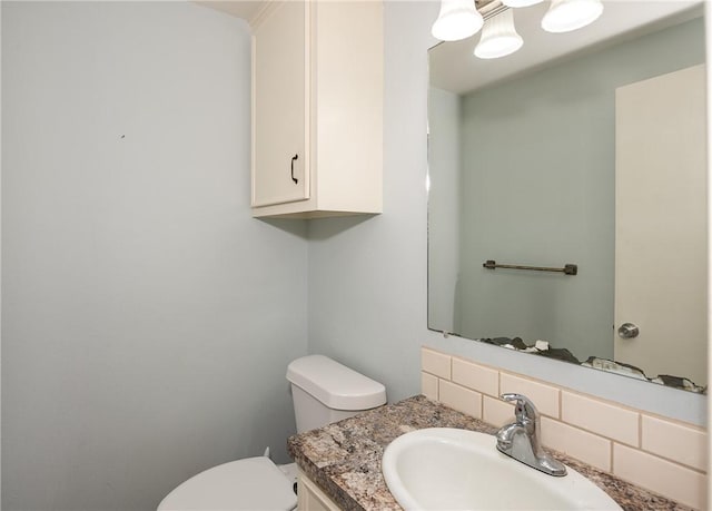 bathroom with vanity, toilet, and tasteful backsplash