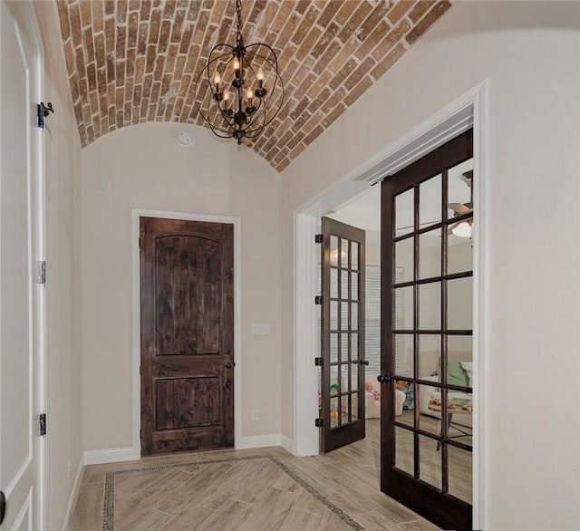 foyer with french doors, brick ceiling, lofted ceiling, a chandelier, and light hardwood / wood-style flooring