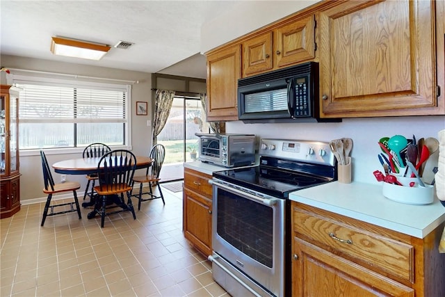 kitchen featuring visible vents, electric stove, black microwave, a toaster, and light countertops