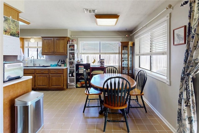 dining area featuring light tile patterned floors, visible vents, a toaster, and baseboards