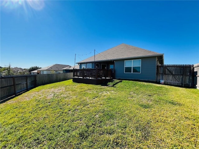 rear view of house featuring a wooden deck and a yard