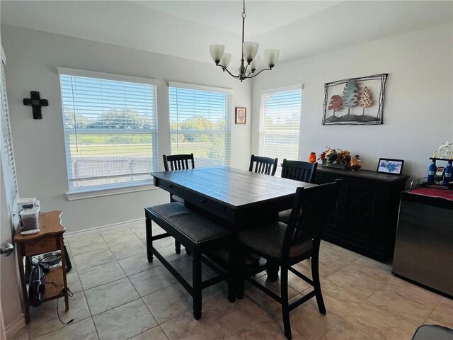 dining area featuring light tile patterned floors, a healthy amount of sunlight, and a notable chandelier