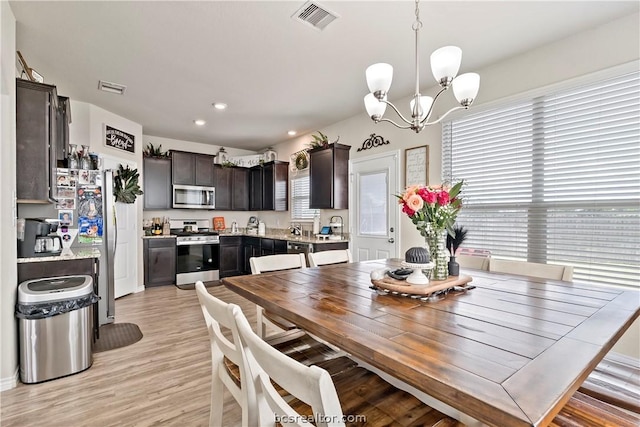 dining space with an inviting chandelier and light hardwood / wood-style flooring