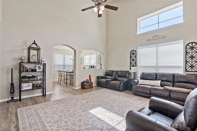 living room featuring hardwood / wood-style floors, ceiling fan, and a towering ceiling