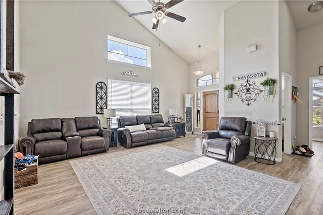 living room with light hardwood / wood-style floors, high vaulted ceiling, ceiling fan, and a healthy amount of sunlight