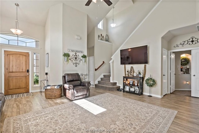 foyer featuring hardwood / wood-style flooring, ceiling fan, a towering ceiling, and a wealth of natural light