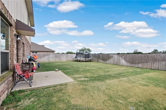 view of yard featuring a trampoline and a patio