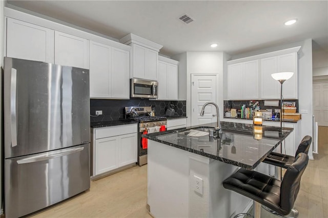 kitchen featuring sink, stainless steel appliances, white cabinetry, and a kitchen island with sink