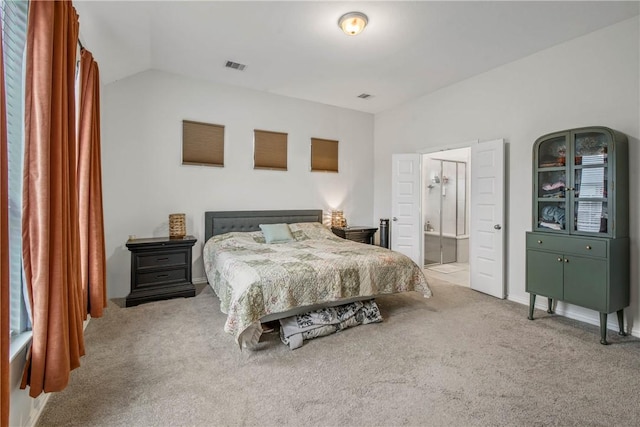 carpeted bedroom featuring lofted ceiling and ensuite bath