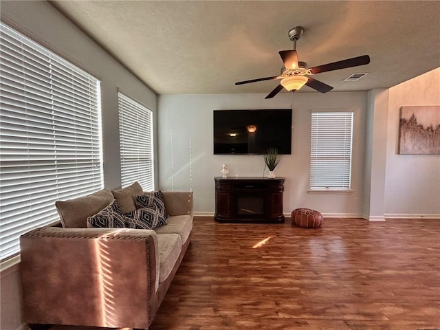 living room featuring ceiling fan and dark wood-type flooring