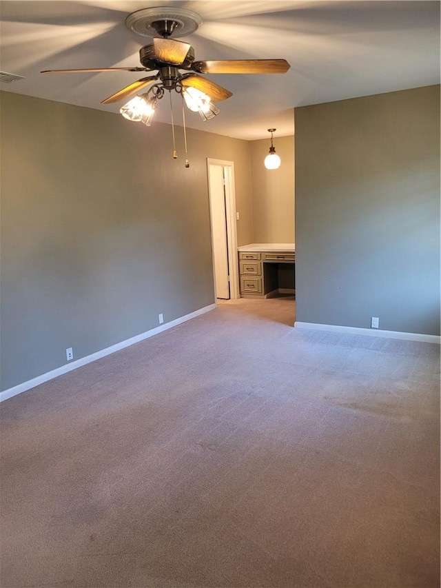 spare room with carpet flooring, ceiling fan, and built in desk