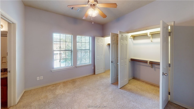 unfurnished bedroom with a closet, light colored carpet, and ceiling fan