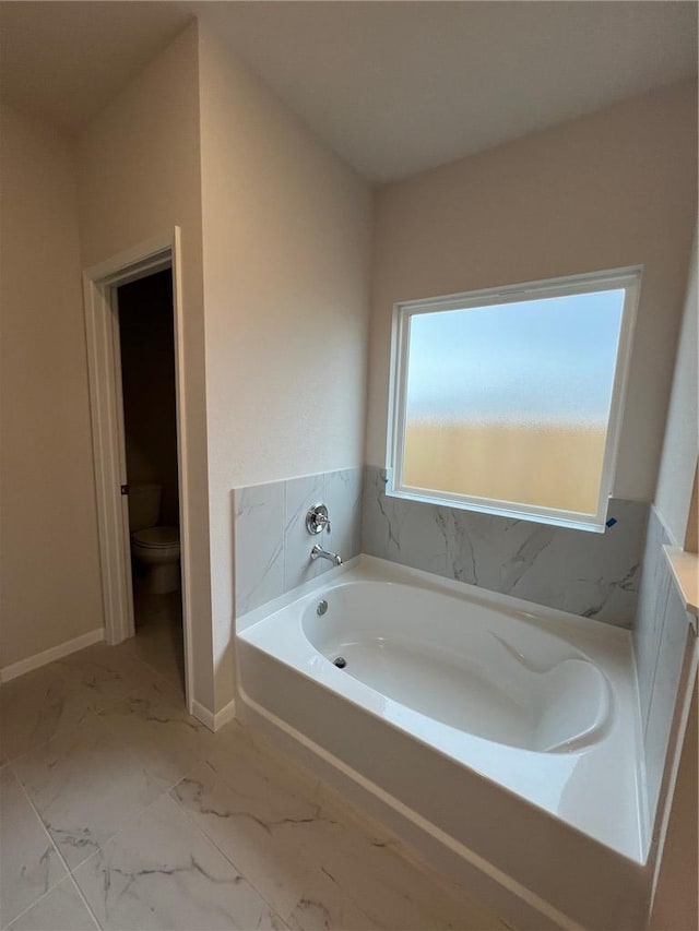 bathroom featuring a washtub and toilet