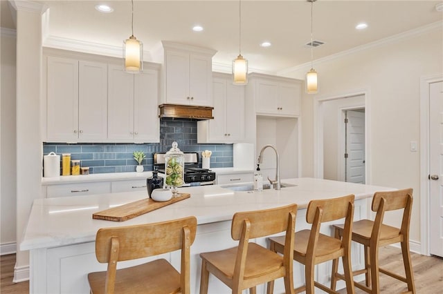 kitchen with a center island with sink, gas range, and hanging light fixtures