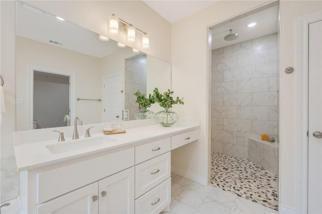 bathroom with tiled shower and vanity