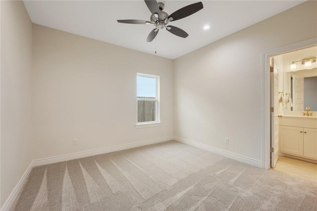 unfurnished bedroom with light carpet, sink, ensuite bathroom, and ceiling fan