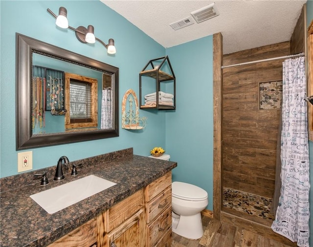 bathroom with vanity, curtained shower, toilet, and a textured ceiling