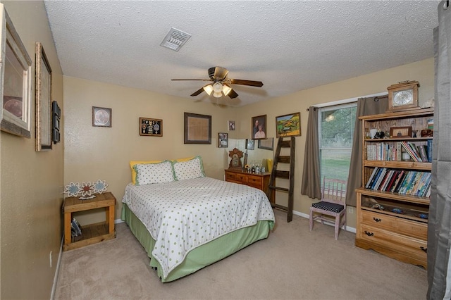 bedroom with ceiling fan, light colored carpet, and a textured ceiling