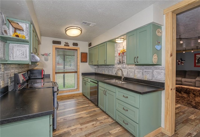 kitchen featuring sink, backsplash, green cabinets, light hardwood / wood-style floors, and stainless steel appliances