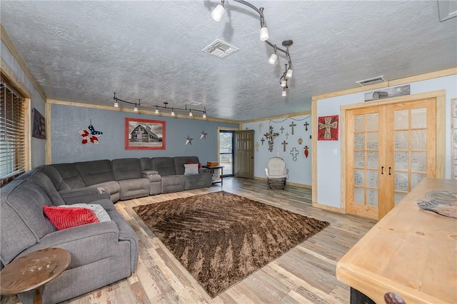 living room with french doors, rail lighting, hardwood / wood-style floors, and a textured ceiling