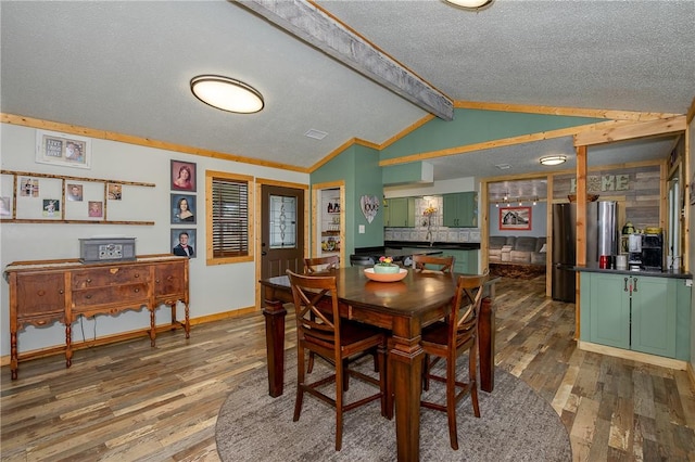 dining room with crown molding, vaulted ceiling with beams, hardwood / wood-style floors, and a textured ceiling