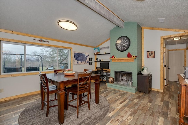 dining area with a brick fireplace, wood-type flooring, lofted ceiling with beams, and a textured ceiling