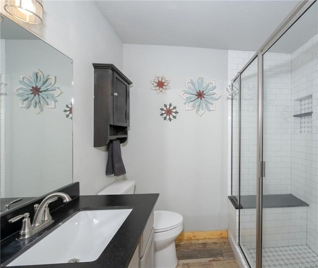 bathroom featuring an enclosed shower, vanity, hardwood / wood-style floors, and toilet