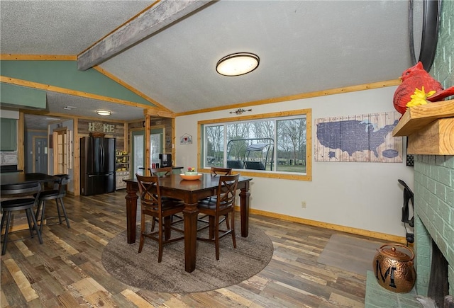 dining room featuring vaulted ceiling with beams, dark wood-type flooring, and a textured ceiling