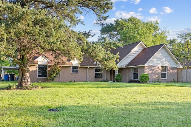 view of front of home featuring a shingled roof, brick siding, and a front lawn