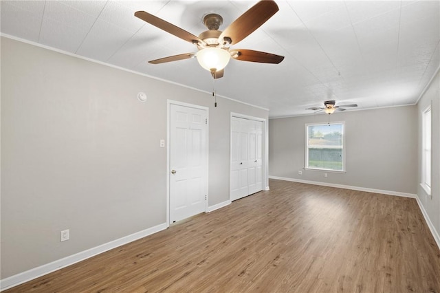empty room featuring baseboards, a ceiling fan, crown molding, and wood finished floors
