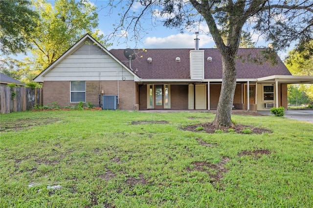 rear view of property with a yard, brick siding, a carport, and central AC