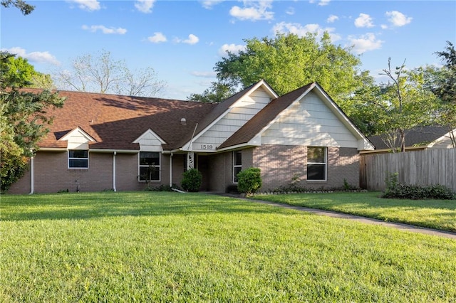 back of property with a yard, fence, and brick siding