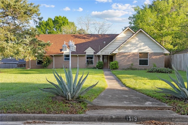 view of front of home featuring a front yard, brick siding, and fence