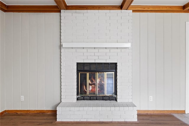 interior details with a fireplace, baseboards, beam ceiling, and wood finished floors