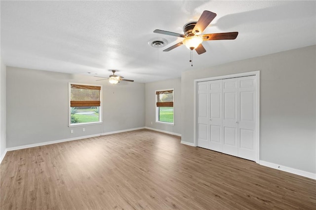 unfurnished bedroom featuring a closet, multiple windows, baseboards, and wood finished floors
