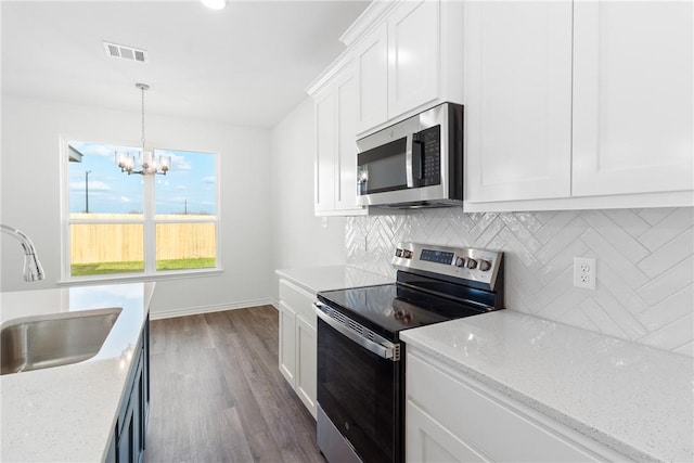 kitchen with appliances with stainless steel finishes, sink, white cabinets, light stone counters, and decorative backsplash