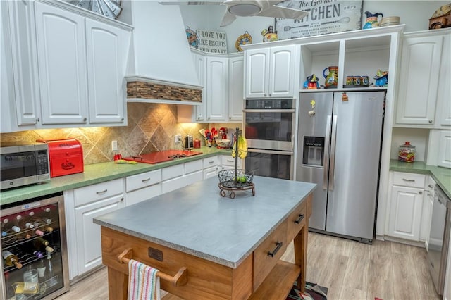 kitchen featuring premium range hood, wine cooler, white cabinets, and stainless steel appliances