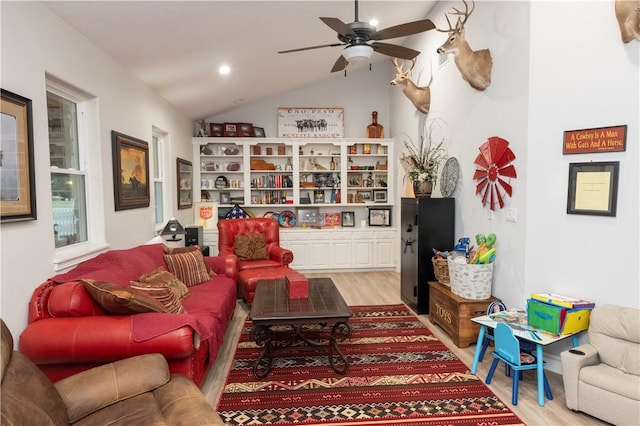 living room with ceiling fan, light hardwood / wood-style floors, and vaulted ceiling