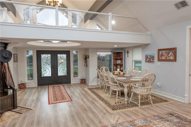 dining area with french doors, high vaulted ceiling, and hardwood / wood-style flooring